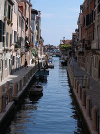 Canal amidst buildings in city against sky