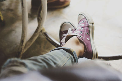 Low section of woman with crossed legs in purple shoes