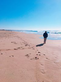 Full length rear view of man walking on shore at beach