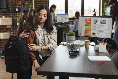 Working mother embracing daughter at office