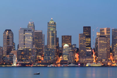 Illuminated buildings in city against sky at dusk