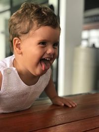 Cheerful baby sticking out tongue at home