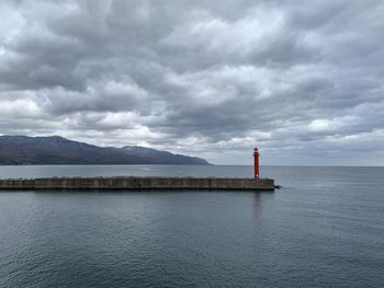 Lighthouse by sea against sky