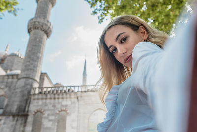 Portrait of smiling woman against mosque and sky