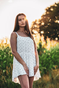 Young beautiful woman in white dress in corn field.