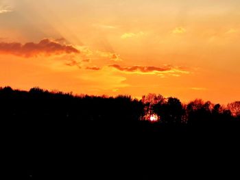 Silhouette trees against dramatic sky during sunset