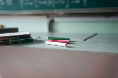 Close-up of chalks and duster on table in classroom