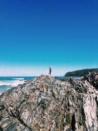 Man standing on cliff by sea