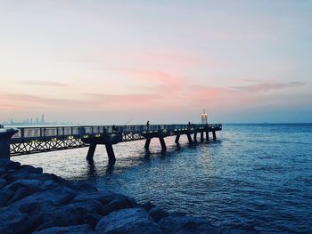 Pier over sea against sky during sunset