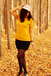 Full length of woman standing by tree during autumn