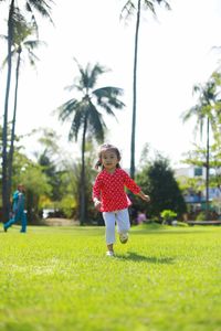 Girl standing on grass against trees