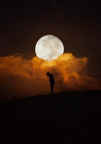 Silhouette person standing against moon at sunset