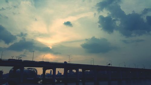 Low angle view of bridge over river in city against sky