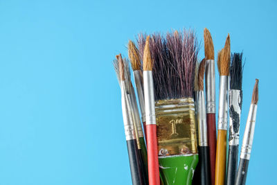Close-up of paintbrushes against blue sky