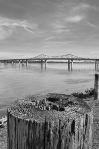 Wooden posts on bridge over sea against sky