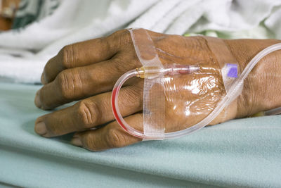 Cropped image of patient with iv drip on bed in hospital