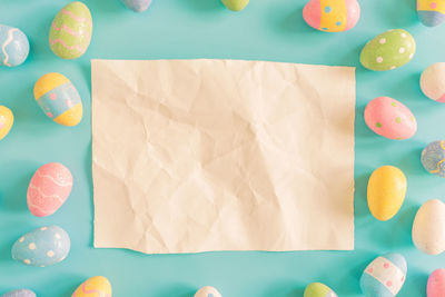 High angle view of paper amidst multi colored easter eggs on table