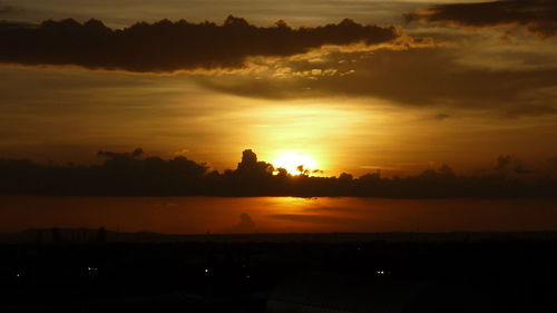 Scenic view of dramatic sky over silhouette landscape during sunset