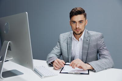 Portrait of businessman using laptop at desk in office