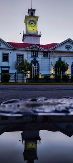 Reflection of building in puddle against sky