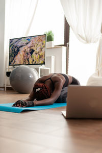 Full length of woman doing yoga at home