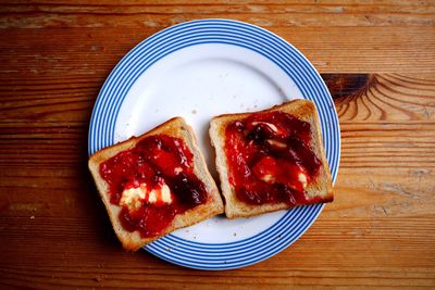 Close-up of strawberry jam with bread in plate on table