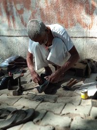 Shoemaker repairing shoe against wall