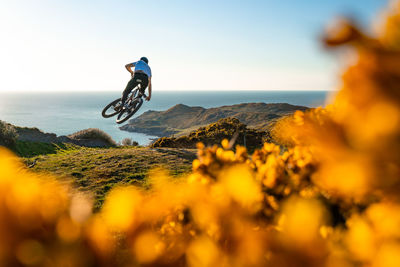 Person riding motorcycle on sea shore against sky