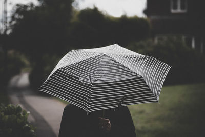 Woman holding umbrella standing against building