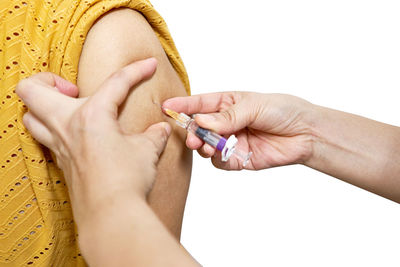 Close-up of woman holding hands over white background