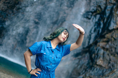 Young woman standing against rock
