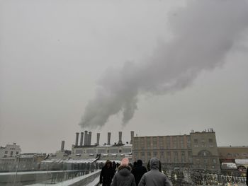 People in factory against clear sky