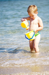 Boy playing with toys while standing at beach