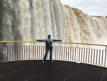 Full length woman standing against waterfall