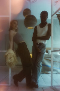 Defocused portrait of young couple posing while standing at doorway of apartment