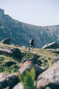 Rear view of man walking on mountain against sky