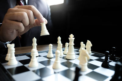 Midsection of person holding chess pieces over board