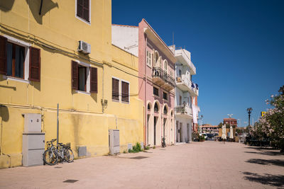 Street amidst residential buildings against blue sky