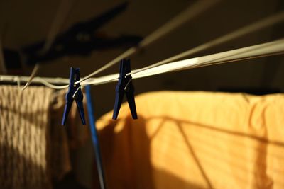 Close-up of pin hanging on clothesline against wall