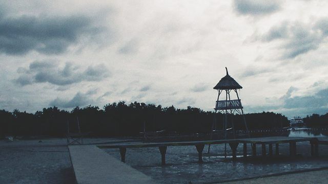 sky, built structure, cloud - sky, architecture, cloudy, building exterior, cloud, water, railing, weather, tranquility, nature, outdoors, tree, the way forward, overcast, bench, day, tranquil scene, walkway