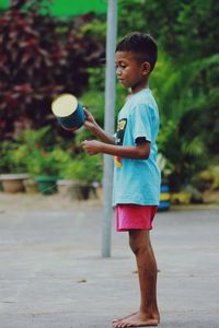 Boy playing with ball on footpath