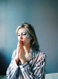 Portrait of beautiful young woman against wall