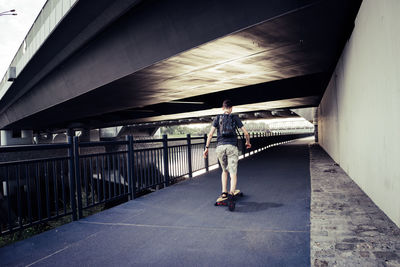 Rear view of man skateboarding on bridge