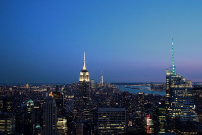 Illuminated cityscape against clear blue sky