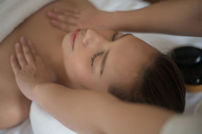 Cropped hands of therapist massaging young woman in spa