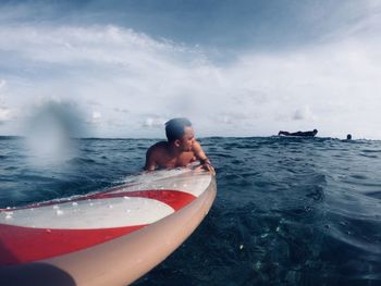 Man surfboarding in at sea against sky
