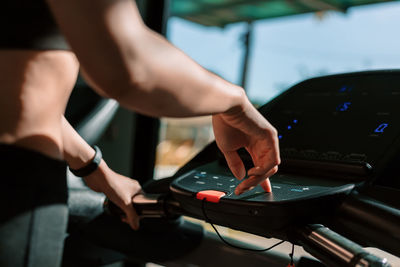 Midsection of woman operating treadmill at home