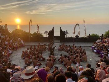 People on shore against sky during sunset