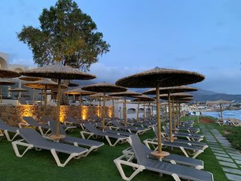 Chairs and tables on beach against sky