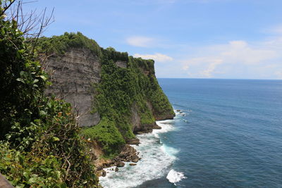 Scenic view of cliff by sea against sky